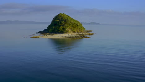 small tropical island in calm blue ocean