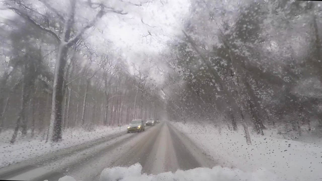 POV of oncoming traffic on icy road in forest in winter