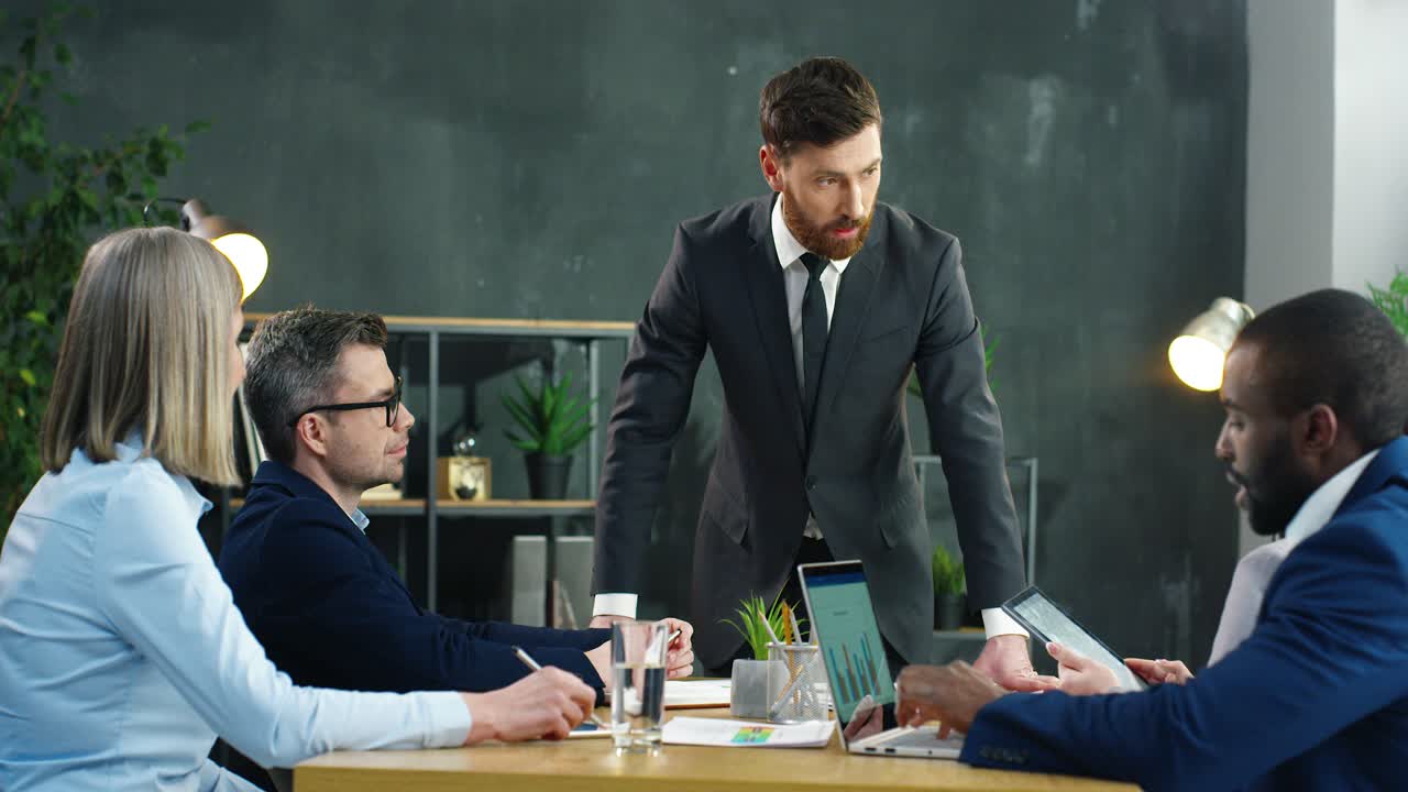 forretningsmann som står ved bordet med multietniske forretningspartnere og snakker om et prosjekt