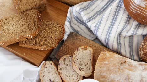 various bread loaves with butter on wooden table