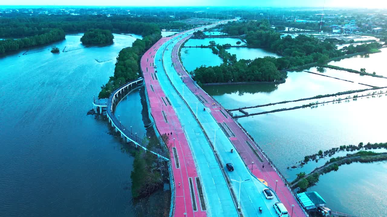 Drone footage of a winding riverside road with cars, mangroves, and water reflections in the Philippines. Ideal for travel, transportation, urban planning, and lifestyle projects
