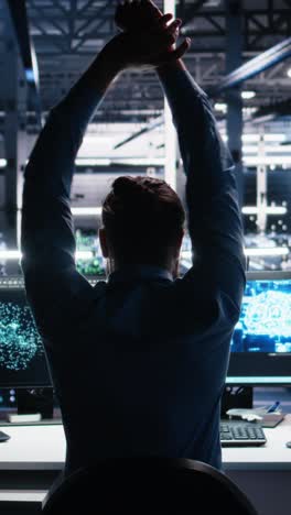vertical video server room technician stretching sore back while using ai at desk