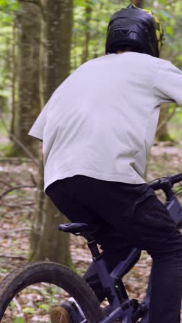 video vertical de un hombre en bicicleta de montaña ciclando a lo largo de un sendero de tierra a través del bosque 10