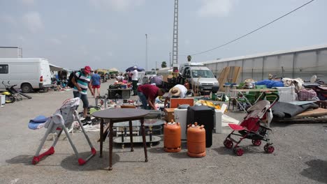 a lively flea market buzzes with activity as shoppers browse through an array of old household items and reusable goods, creating a vibrant, nostalgic atmosphere.