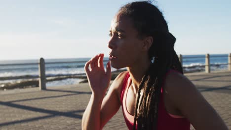 African-american-woman-in-sportswear-resting-on-promenade-by-the-sea