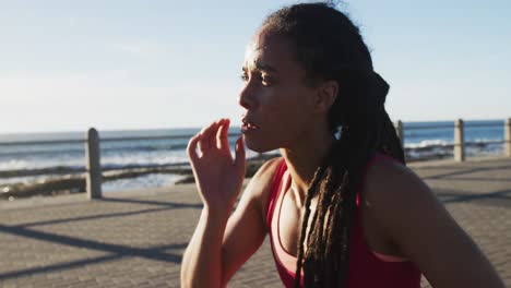 mujer afroamericana en ropa deportiva descansando en el paseo marítimo por el mar
