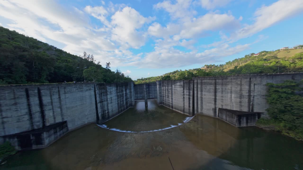 Hatillo Dam, concrete structure surrounded by lush greenery, Cotui in Dominican Republic Drone flying under bulkheads, Aerial FPV
