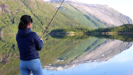 woman fishing on fishing rod spinning in norway.