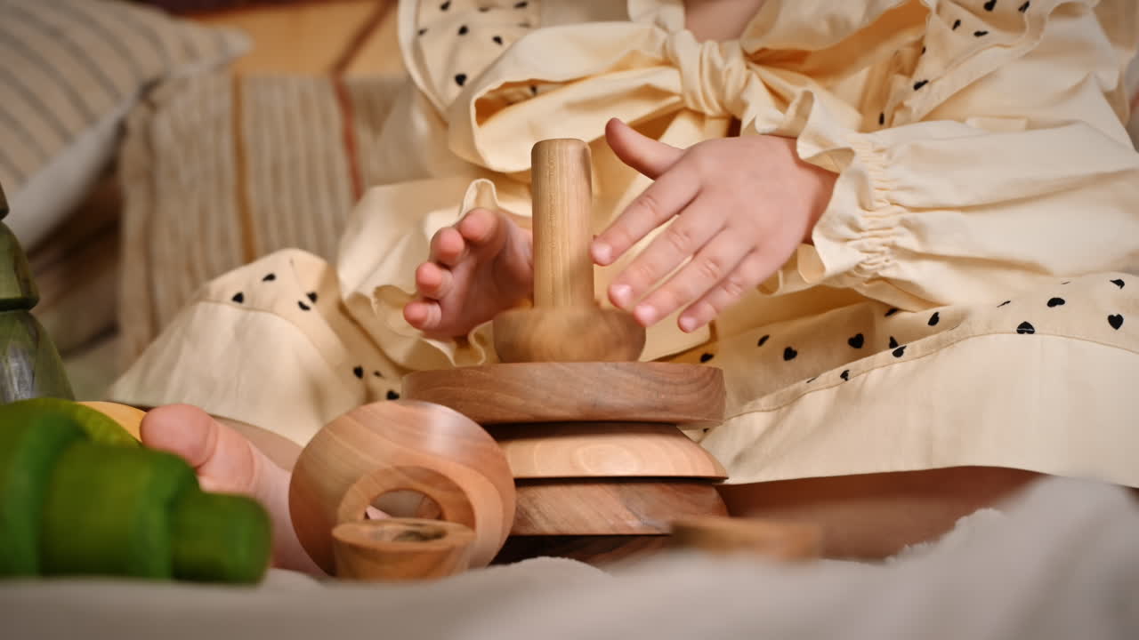 Little girl's hands playing with a wooden stacking jug. Ecological and sustainability concept
