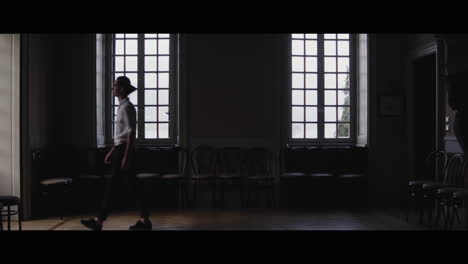 man walking in a grand room with large windows