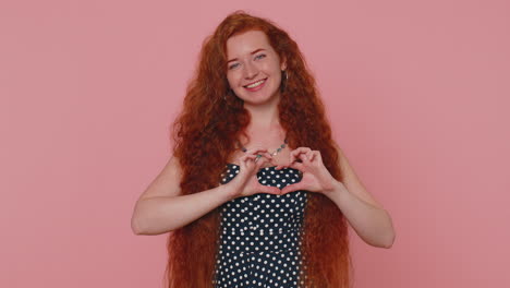 la chica roja sonriente hace un gesto de corazón demuestra un signo de amor expresa buenos sentimientos y simpatía