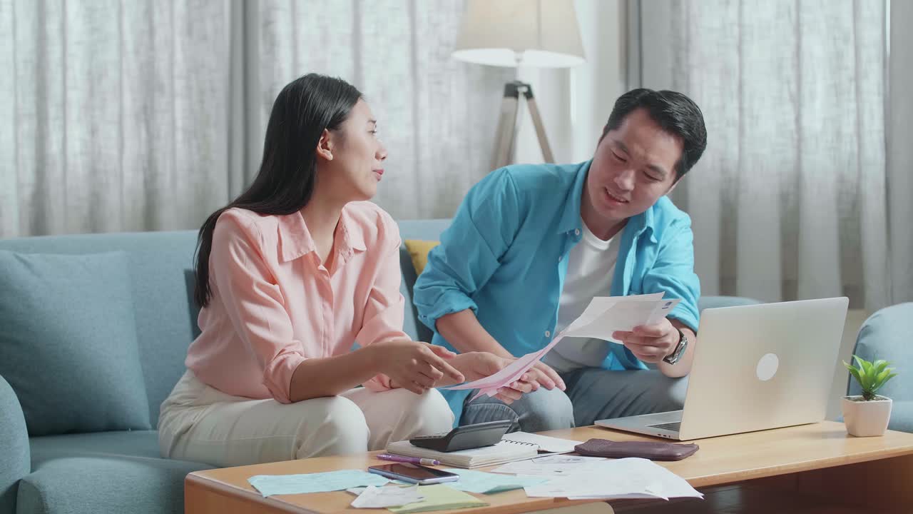 Asian Couple With A Laptop Arguing About The Bill Then Having Headache Due To Financial Problem