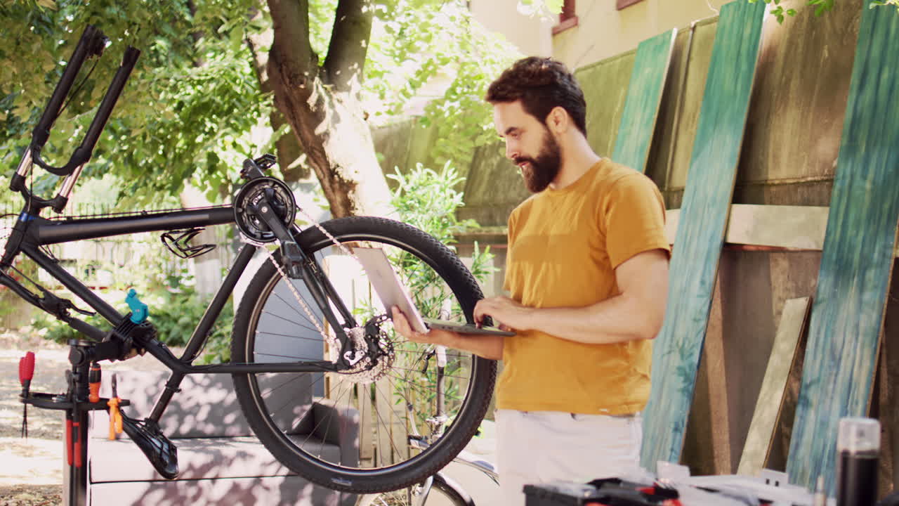 hombre manteniendo una bicicleta con una computadora portátil