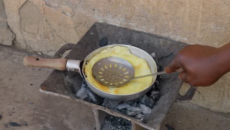 hacer una tortilla de huevo en una estufa de carbón, con banku como plato de acompañamiento