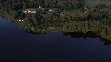 Una-Impresionante-Vista-Desde-Un-Dron-De-La-Aldea-De-Katvari-Al-Atardecer,-Destacando-El-Tilo-Katvari-Junto-Al-Lago