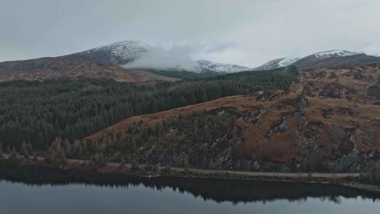Veduta aerea 4K di un lago montano. Loch Garry, Altopiani Scozzesi con montagne innevate e foreste di pini