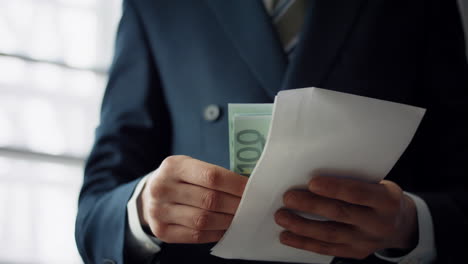 man putting bribe envelope in office close up. hands placing euro for corruption