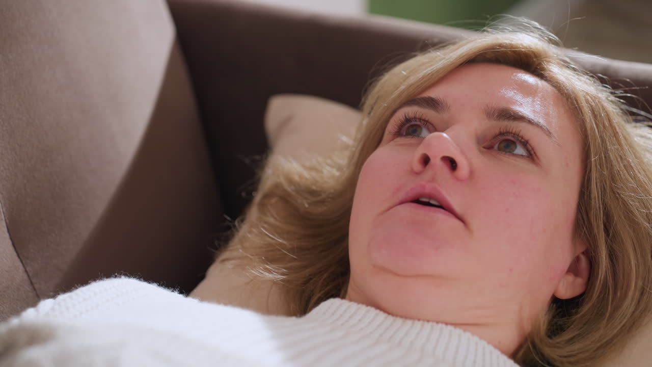 Woman lying faced up on relaxation bench hands gesturing as she converses with empathetic tone soft lighting conveying introspection mental health focus healing dialogue serenity support