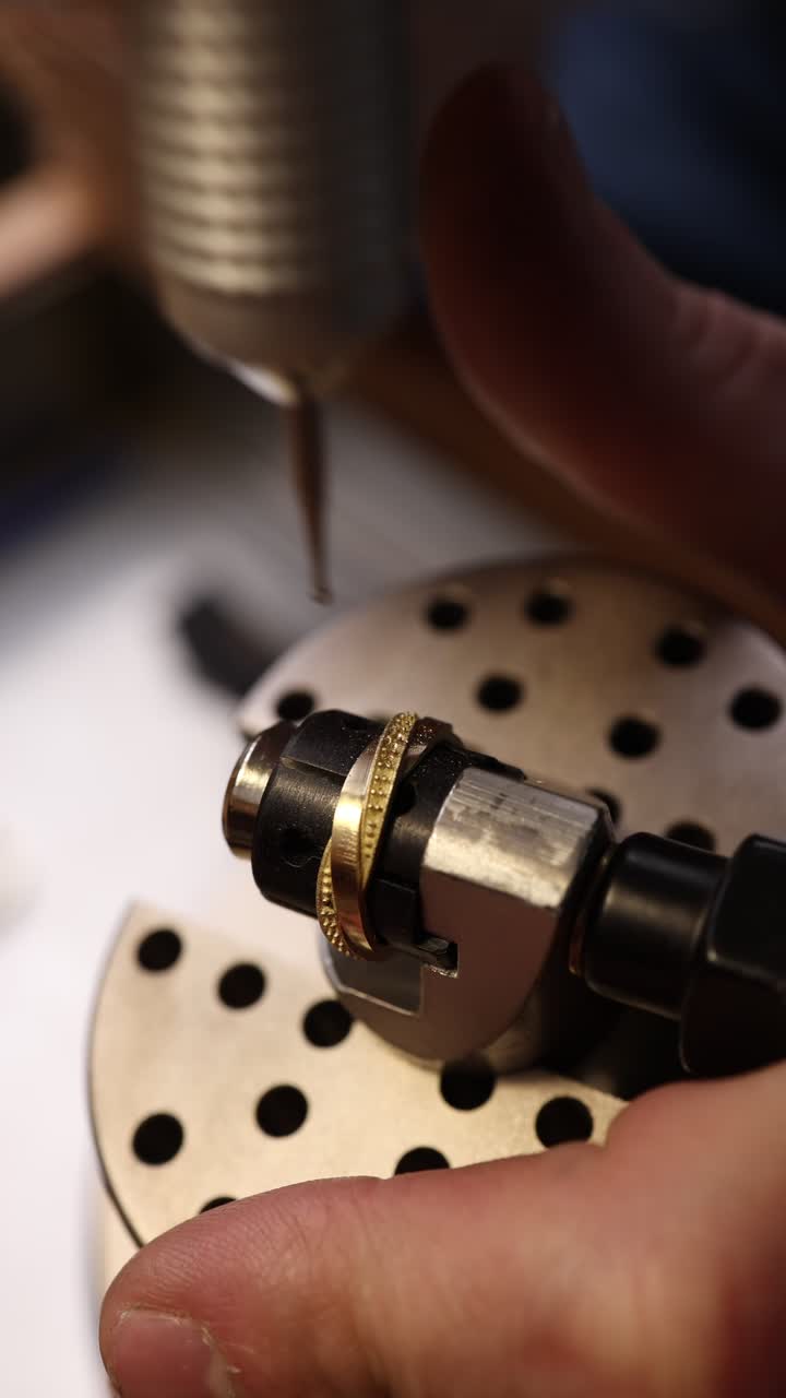 Primo piano di un gioielliere che incide un anello d'oro con uno strumento di precisione