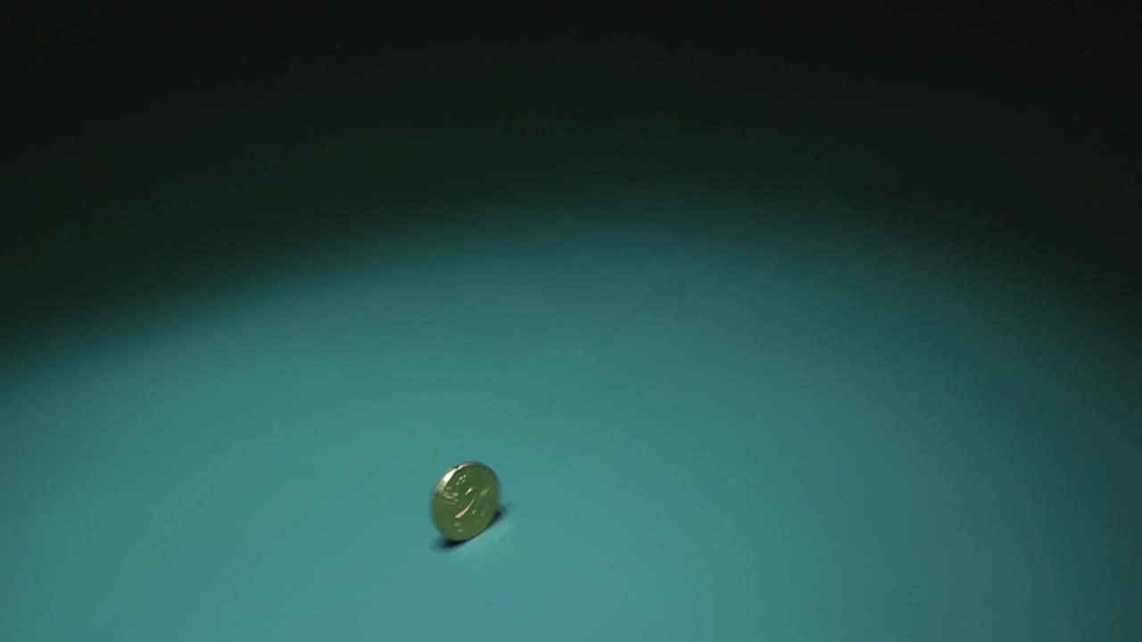 las imágenes muestran una moneda de 20 centavos de euro girando rápidamente sobre un fondo verde vibrante