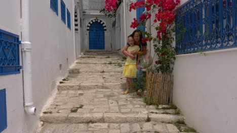 young mother together daughter posing for photo on narrow street background