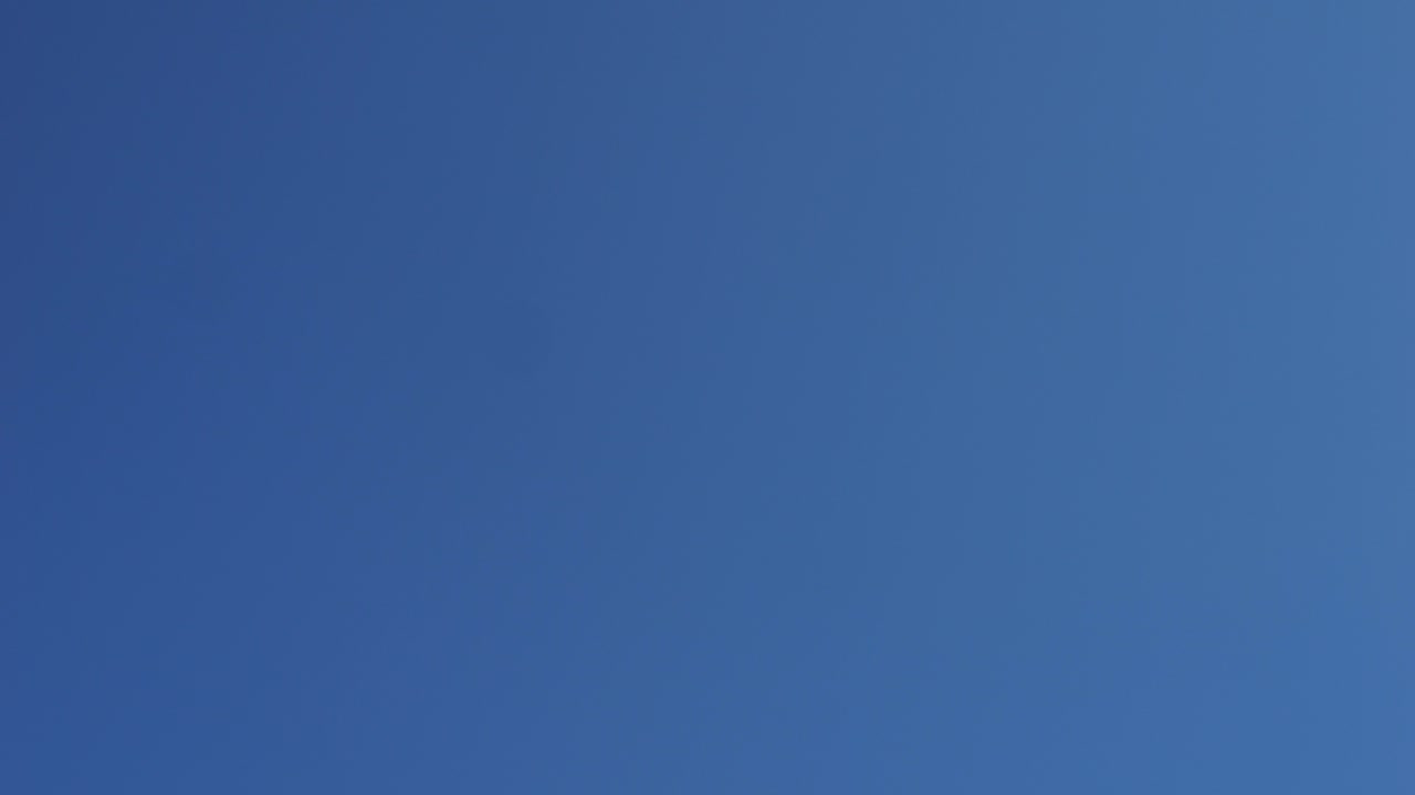 Hand holding a rock against a clear blue sky