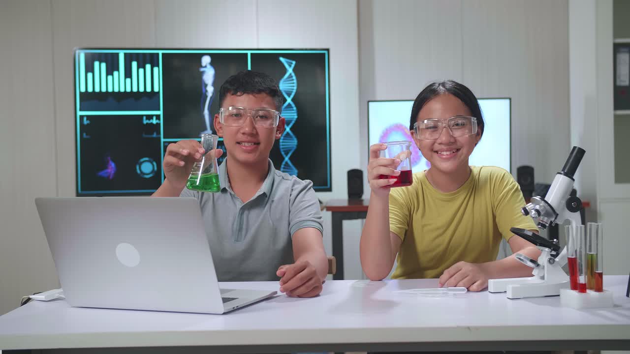 Young Asian Boy And Girl Smiling To Camera While Holding Tubes In Classroom. Study With Scientific Equipment. Education Concept