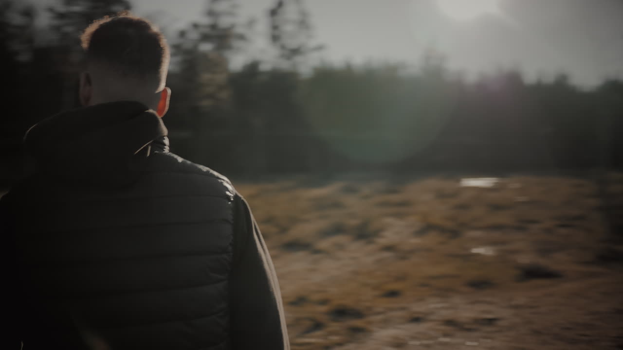 fotógrafo masculino enfocado e inspirado camina rápido con una cámara sin espejo dslr y lente para tomar fotos de paisajes al atardecer