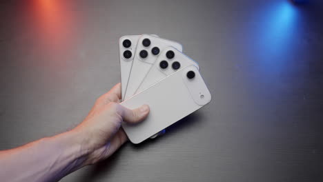 hand holding multiple white smartphones