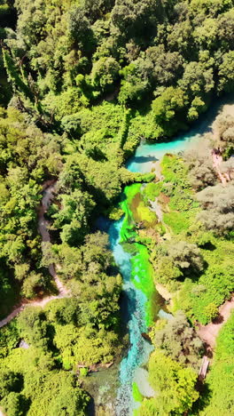 flight above the rocky landscape crossed by the wavy thin turquoise river. sunny scenery of picturesque nature of albania. vertical video.