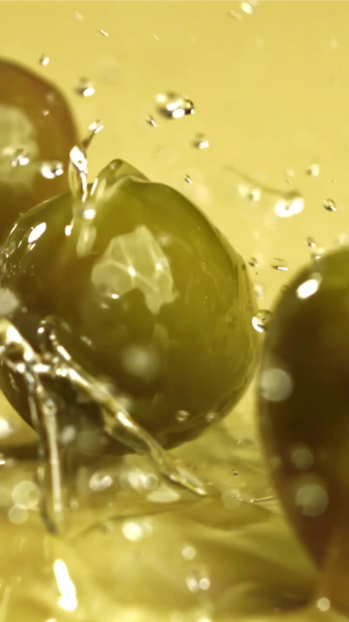 Primo piano di olive verdi che schizzano nell'olio d'oliva dorato