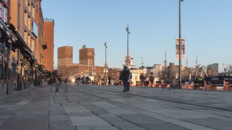 Time-lapse-of-pedestrians-walking-along-Oslo-promenade-at-sunset,-zoom-in