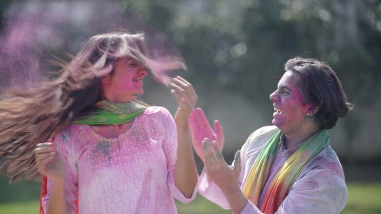 Indian man put colors on his wife face from back