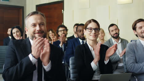 Business-People-In-Audience-At-The-Conference-In-The-Hall-And-Applauding-Cheerfully-To-The-Speaker