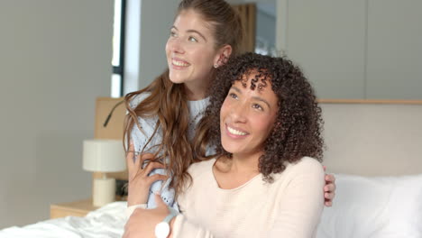smiling lesbian couple embracing and relaxing together on bed at home