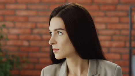 portrait of the young brunette businesswoman looking at the side, then turning her head and smiling to the camera