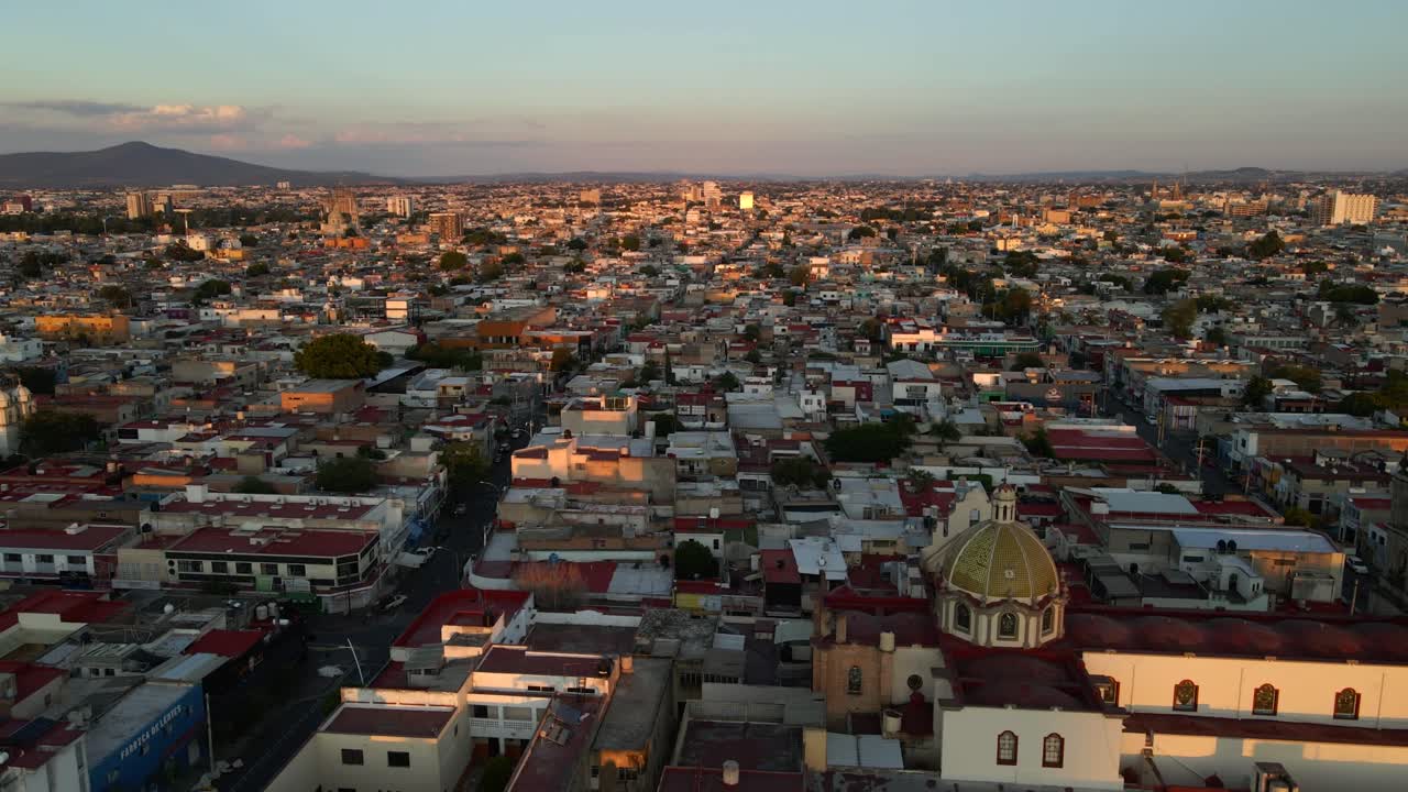 Guadalajara by, Jalisco, Mexico ved solopgang. Byområdet strækker sig mod horisonten under klar morgenhimmel. Luftopstigning med nedadgående tilt i 4K.