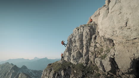 excursionistas que descienden de la roca en las montañas con equipo de rescate naranja completo, cielo azul claro