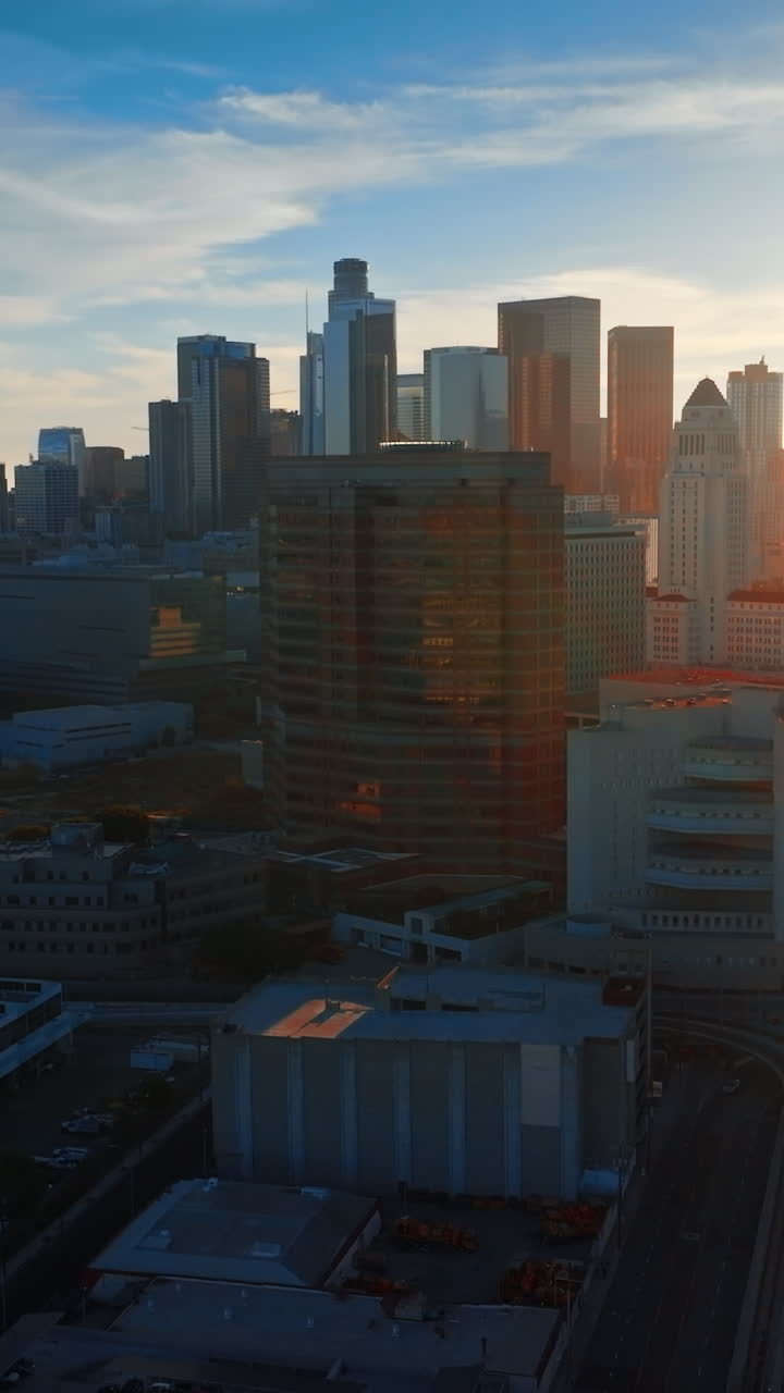 Spindrift cloudscape over the beautiful Los Angeles downtown. Beautiful skyscrapers dropping shadows on the city. Sunny sky at backdrop. Vertical video