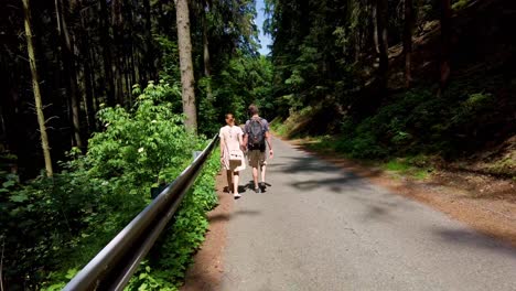 Loving-couple-of-boy-and-girl-with-backpacks-walking-on-the-road-in-nature-holding-hands