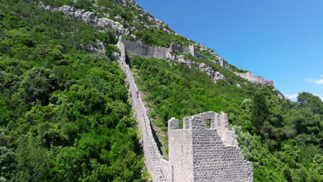 person going down the ston walls in the mountain in croatia. - aerial shot