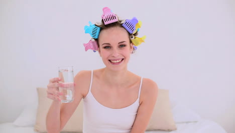 young model in hair rollers drinking glass of water