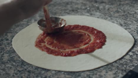 chef anónimo untando salsa de tomate en la pizza