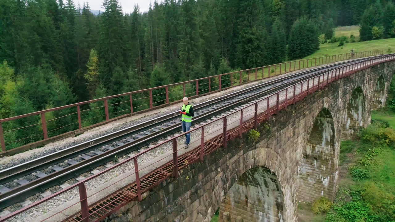 trabajador en un puente ferroviario en las montañas