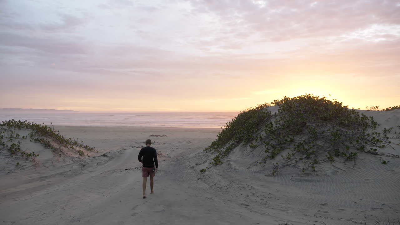 남아프리카 동부 런던의 일출 해변에서 걷는 남자의 실루엣