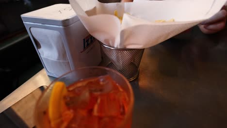 papas fritas y un cóctel en un bar.