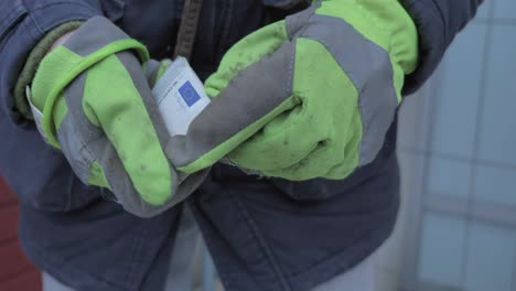 close up of worker with working gloves counting five euros bills outdoor