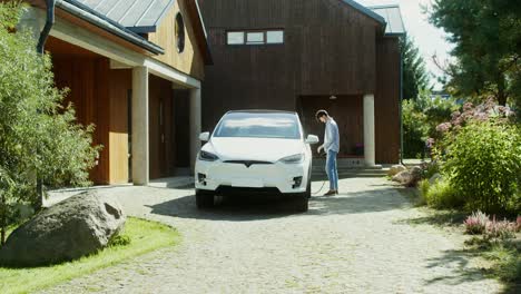 man charging electric car at home