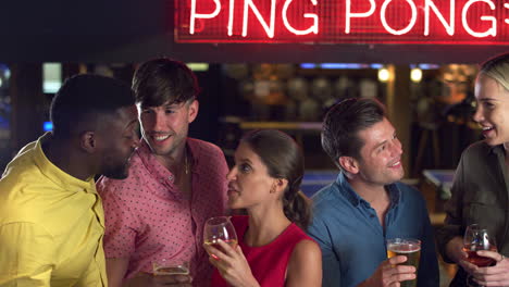 grupo de amigos que se reúnen para tomar bebidas y hacer un brindis en el bar en la noche