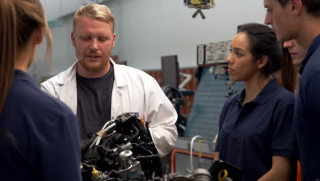 tutor explaining how engine works to group of apprentices